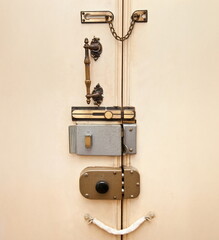 Old wooden door secured by multiple locks, bolts, and a chain, representing a vintage concept of home security