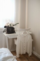 A charming bedroom corner with an elegant white blouse and lovely floral decor for freshness