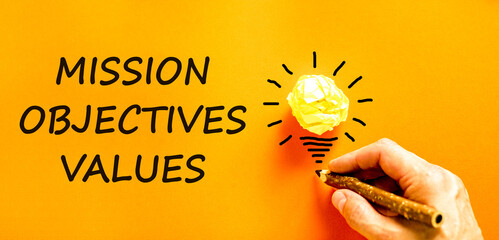Mission objectives values symbol. Concept words Mission Objectives Values on orange paper....