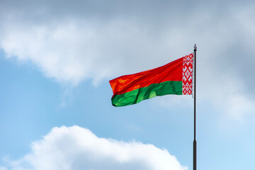 Flag of Belarus is waving against a blue sky with white clouds, symbolizing national pride and patriotism.