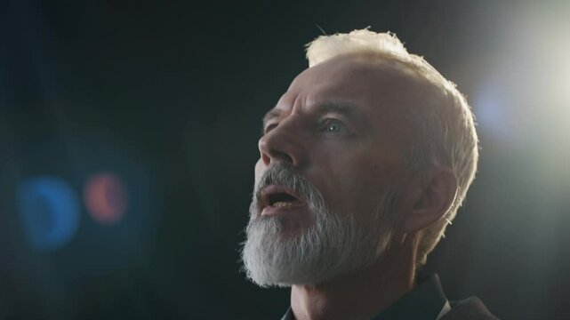 Closeup of middle-aged man with beard on face sitting with digital tablet in hand asking question during business meeting