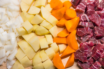 Chopped vegetables and beef on wooden board