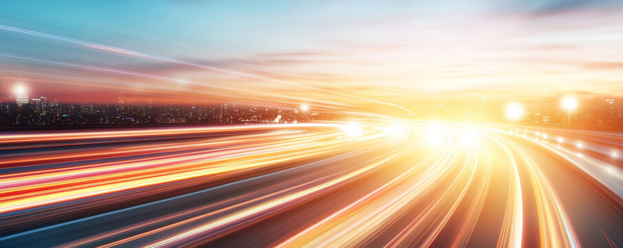 Vibrant light streaks blurring across highway lane markings during golden hour, urban skyline silhouetted against dimming sky