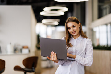 Portrait of a happy businesswoman working on laptop in office