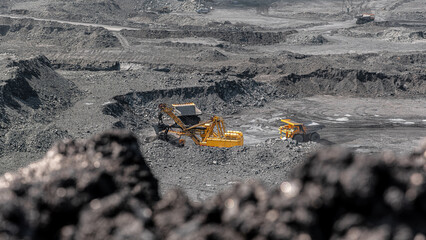 Big dump truck in quarry. Large yellow mining truck at work site. Loading coal into body truck....