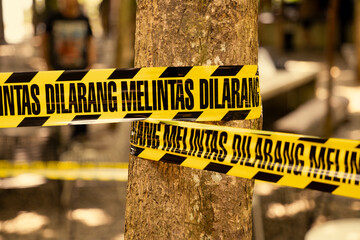 A yellow and black plastic ribbon reading “No Trespassing” was tied to the tree trunk. To deter people from passing through the area.