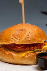 Two burger sliders placed on a white plate. Very tasty burgers with melted cheese, lettuce, tomato and sauce