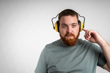Caucasian Construction Worker in His 20s Wearing Noise Cancellation Safety Headphones While Working Within Construction Site.