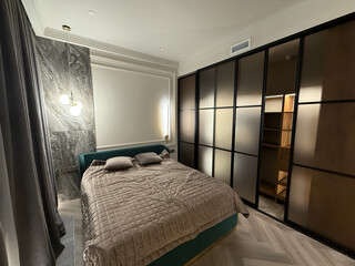 This cozy bedroom features a plush bed adorned with soft pillows, complemented by a sleek, modern closet illuminated from within, enhancing the room's ambiance and elegance.