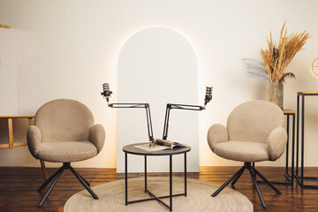 Podcast setup featuring microphones and cozy chairs in a well-lit studio environment