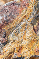 The background is a beautiful rough stone texture in close-up with bright colors of mineral inclusions