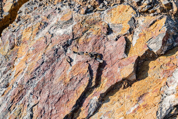 The background is a beautiful rough stone texture in close-up with bright colors of mineral inclusions