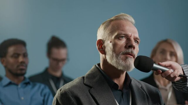 Mature Caucasian man with beard on face having question regarding presentation at conference