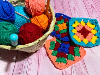 Crochet granny square, clews and hook on crochet blanket background photo	
