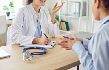 Smiling young woman talking, female patient listening to doctor therapist at meeting, sitting at...