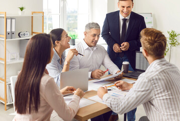 Fototapeta premium Happy business team working together in the office during a meeting or briefing. Successful and confident group in conversation, emphasizing effective communication and collaboration.