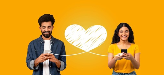 A couple sits together, smiling as they text each other on their smartphones. The vibrant...