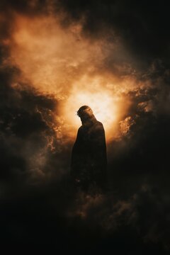 Powerful silhouette of Jesus against dramatic, stormy sky with rays of light breaking through the clouds. Deep contrast, epic and emotional mood. Good Friday concept with copy space.
