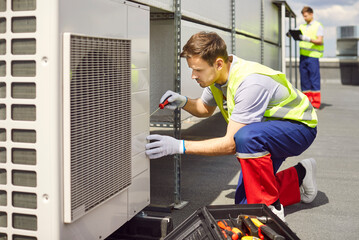 Repairman or electrician performing maintenance, repair, or inspection of an HVAC system on the...
