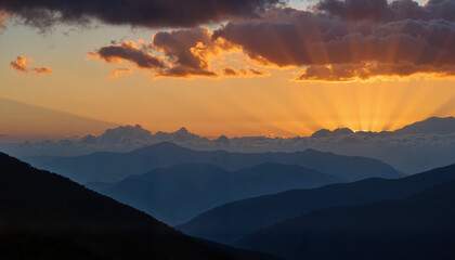 Fototapeta premium Glowing evening clouds above silhouetted mountains, dreamlike serenity