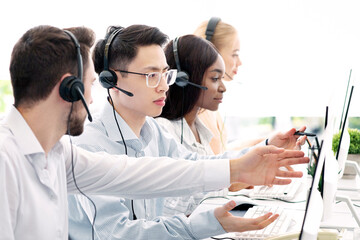 Customer support service concept. Helpline operator consulting his colleague at call centre....