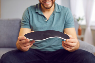Man holding new orthopedic insole sport shoe for walking, running, close up. Foot care, flat feet,...