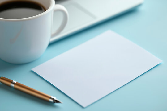 Coffee cup near blank paper and pen on a blue workspace table