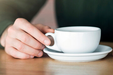 Cropped of guy hands holding cup of coffee at cafe