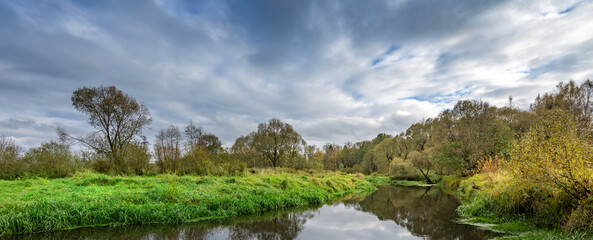 River with trees on either side and a cloudy sky in the background