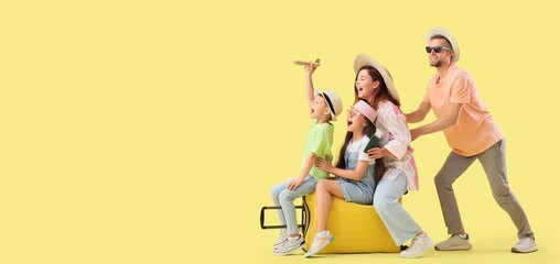 Fototapeta premium Happy family with suitcase on yellow background with space for text. Travel concept