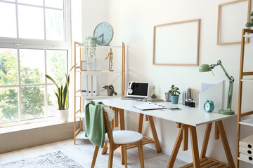 Interior of light office with workplace and shelving unit