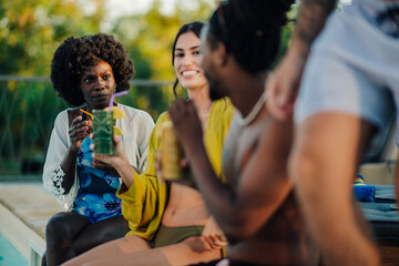 Friends enjoying cocktails by the pool during summer vacation