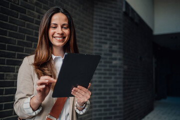 Fototapeta premium Smiling businesswoman using digital tablet in modern office corridor