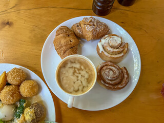 Delicious breakfast with coffee, croissants and cinnamon rolls on wooden table