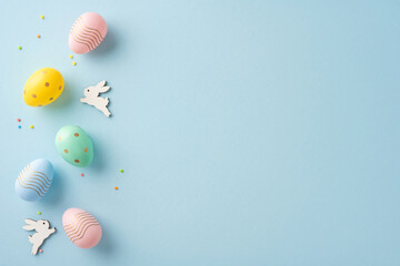 Colorful decorated Easter eggs and wooden bunny figurines artfully displayed on pastel blue