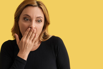 Scared mature woman on yellow background, closeup