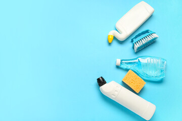 Bottles of detergent and sponge on blue background