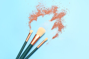 Fototapeta premium Makeup brushes and highlighter on blue background