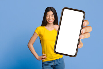 Great App. Happy Young Korean Woman Holding Smartphone With Blank Black Screen, Standing Over Purple Studio Background With Free Space, Mockup