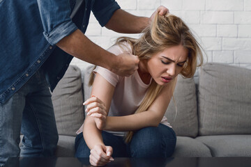 Domestic violence. Man threatens woman by grabbing her hair, woman face expresses pain, cropped