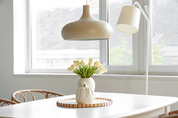 Vase with beautiful tulip flowers on dining table in light room
