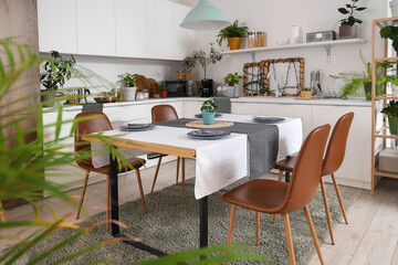 Interior of modern kitchen with green plants, dining table and counters