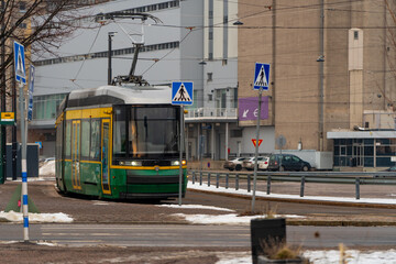 Electric tramway modern public transport in euROPEAN CITY OF hELSINKI in Finland. Cold time in winter public commuting. New modern tram on tramway in European city. Green and yellow tram