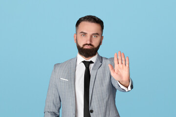 Portrait of serious office employee gesturing STOP, expressing denial on blue studio background....