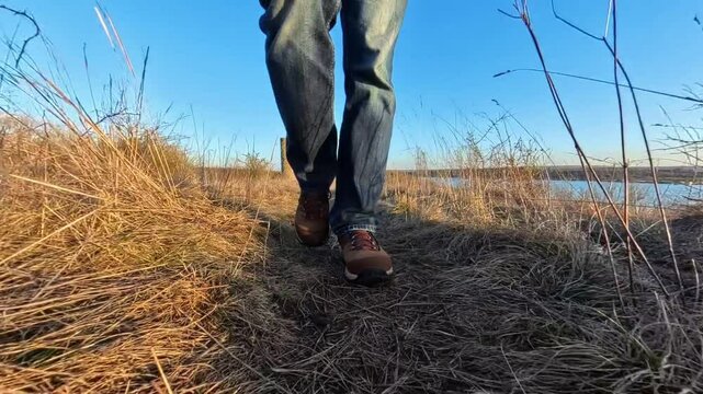 Mann l&auml;uft mit Wanderschuhen auf einem engen Pfad durch die Natur