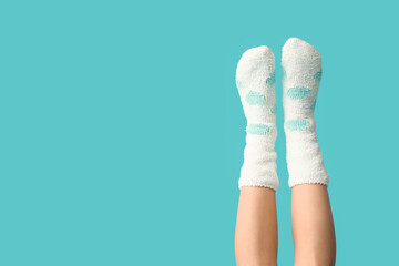 Legs of young woman in warm white dotted socks on blue background