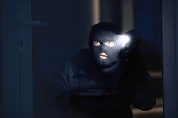 Shadowing Concept. Criminal wearing black balaclava watching you through window or door, using...