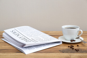 Newspaper with cup of coffee and beans on wooden table