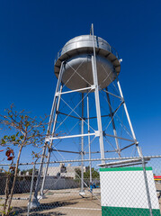 A grey elevated tank above a water well