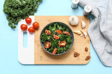 Composition with bowl of tasty kale salad, tomatoes and spices on color background